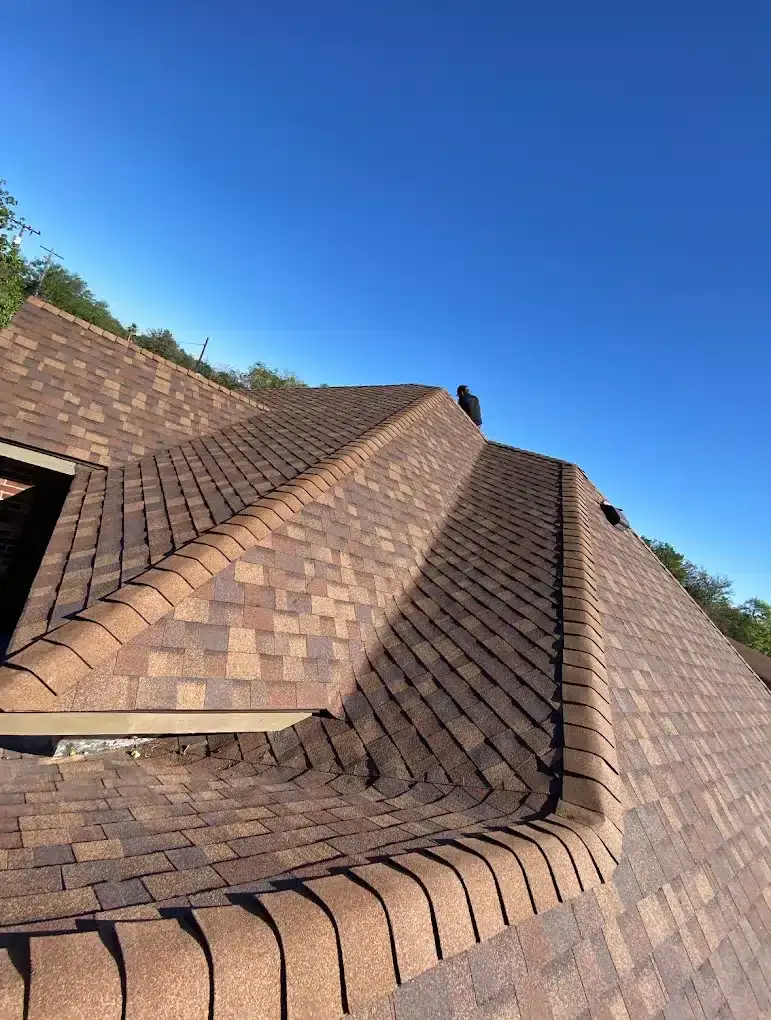 Buffalo Roofing & Exteriors recent roofing project with brown shingles and a worker on the roof.