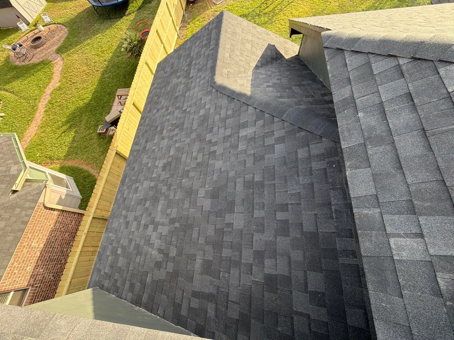 Newly installed asphalt shingle roof and surrounding residential yard