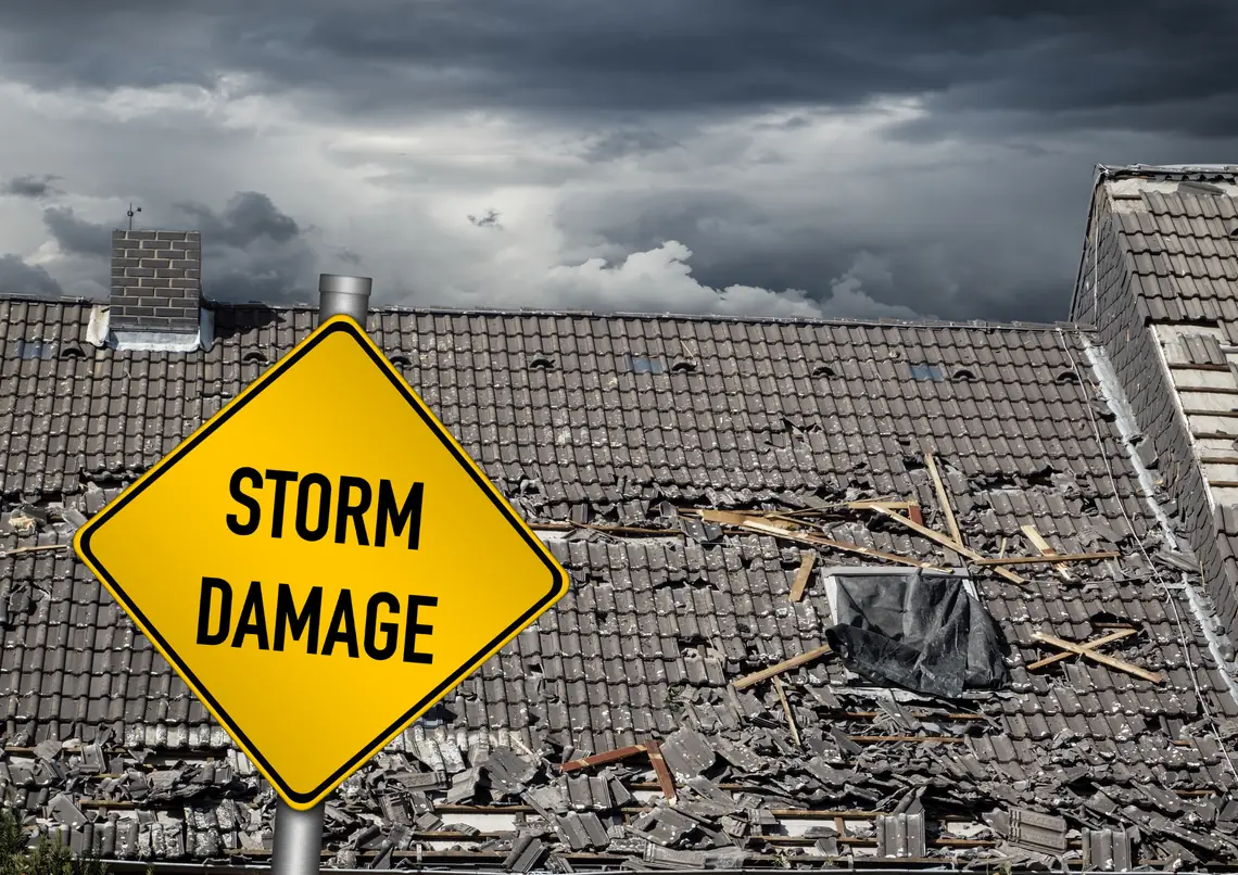 Storm damage warning sign in front of a roof with broken tiles