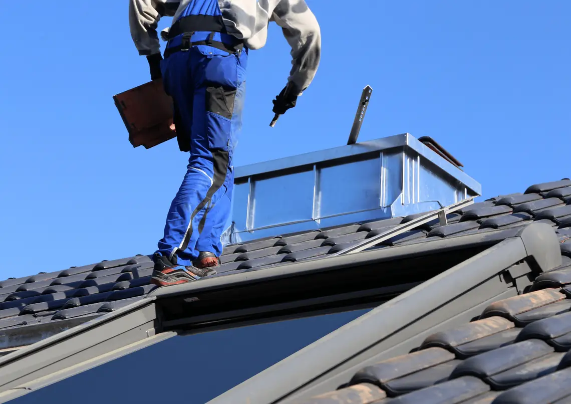 Roofer walking on a tile roof next to a skylight