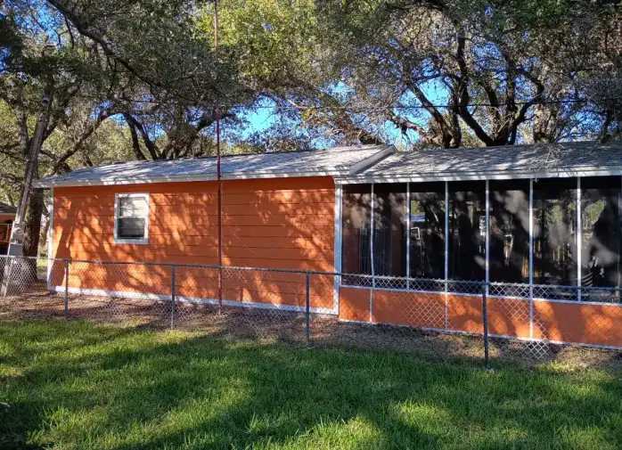 Exterior of orange house with screened porch and roofing project