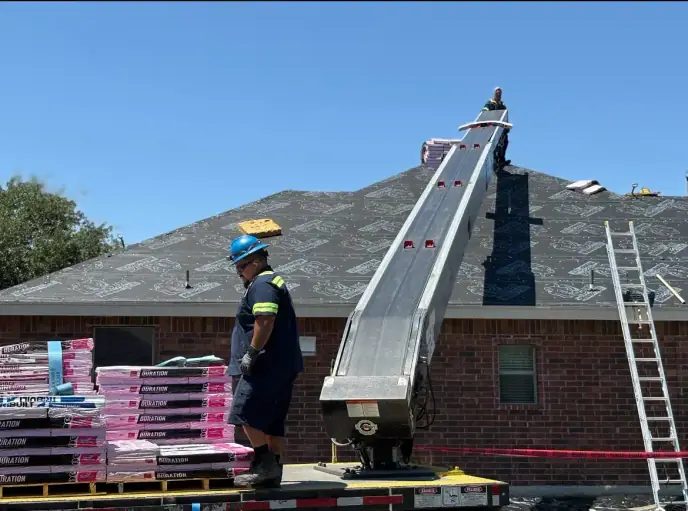 Roofing crew installing shingles on a roof with a conveyor belt and materials.