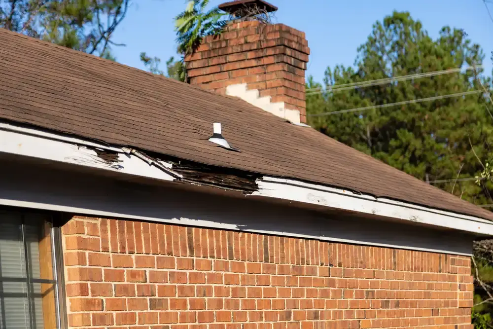 Damaged fascia board with rot and deterioration along the roofline, highlighting potential moisture issues and the need for prompt roof repair services.