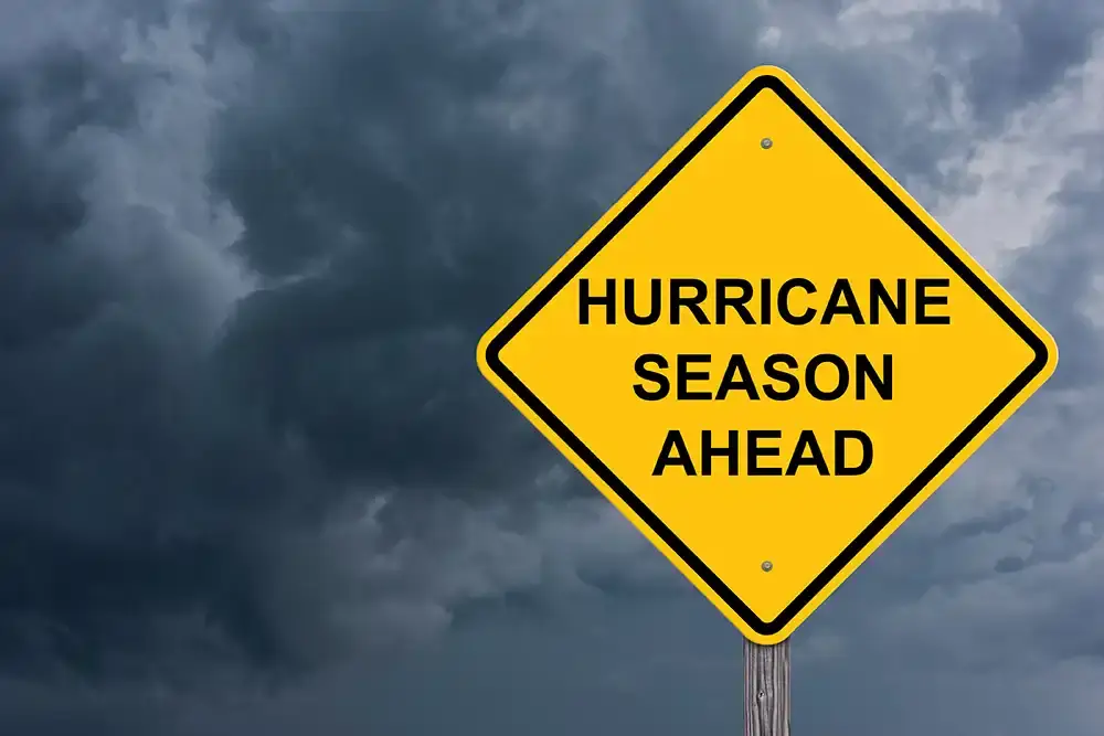Yellow "Hurricane Season Ahead" road sign under dark storm clouds