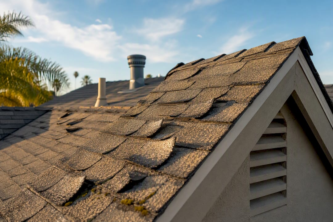 Close-up of curled shingles and ridge vent in summer