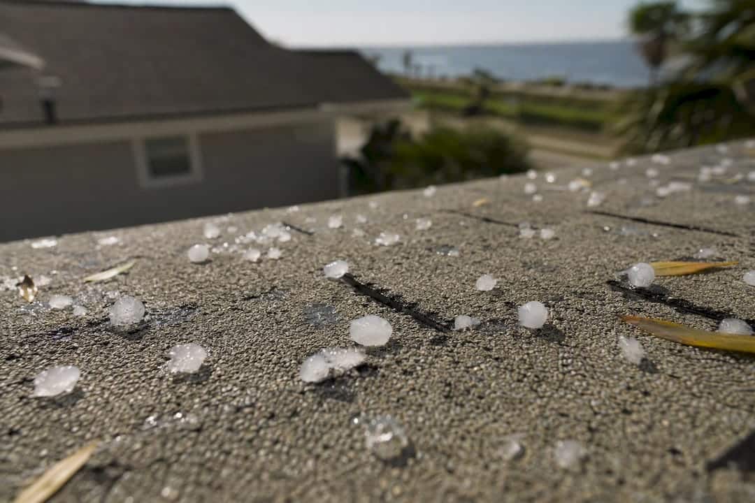 Close-up hailstones on damaged asphalt shingles