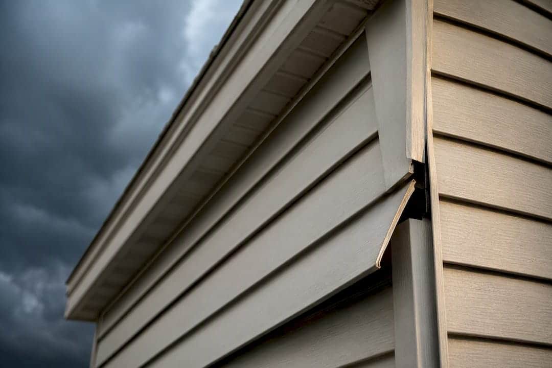 Loose vinyl siding panel after wind damage